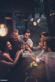 Group of happy friends toasting with alcohol during a party in the backyard.